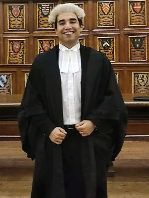 Aleks smiling in a wig and gown.