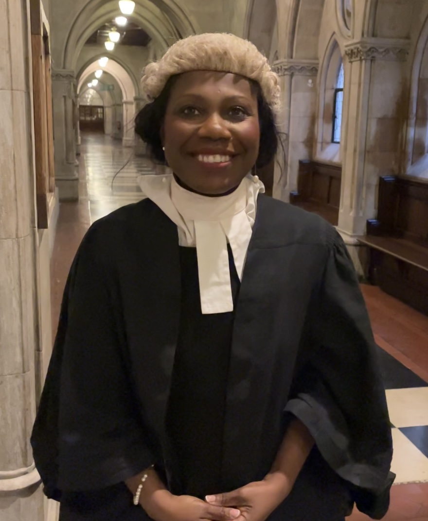 Sally smiles wearing a wig and gown.